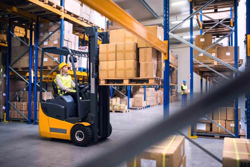 Forklift operator lifts a pallet of boxes to move to a high shelf